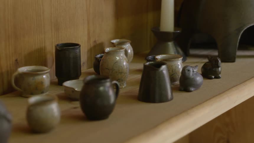 Hand made ceramics and pottery sits on a wooden shelf