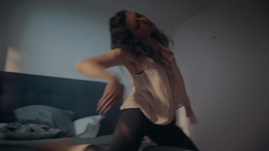A woman is dancing on the bed