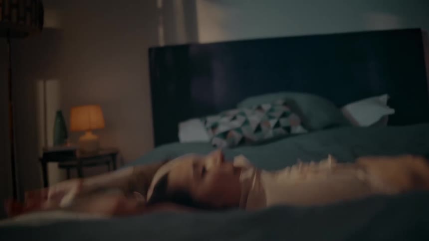 A woman jumping backwards onto her bed