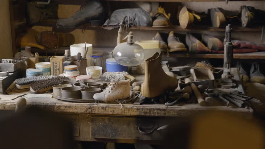 Shoes and cobbler tools sit on a workbench