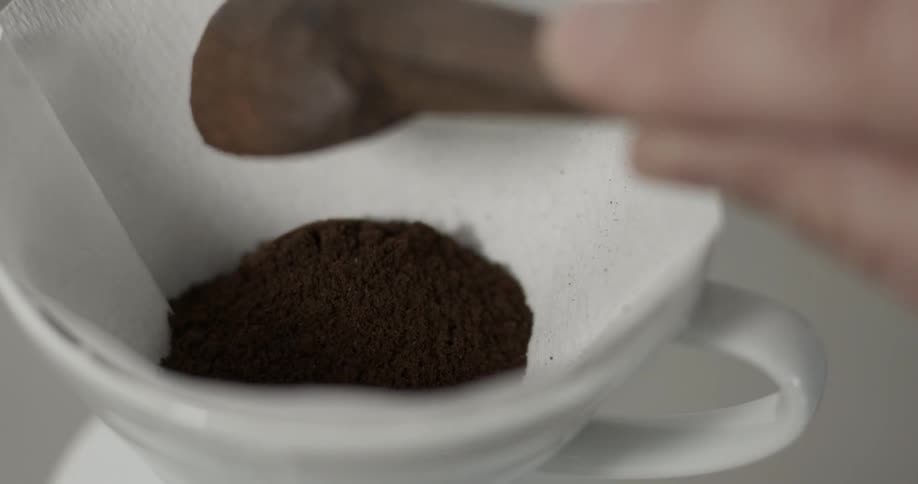 Coffee grounds are scooped into a filter