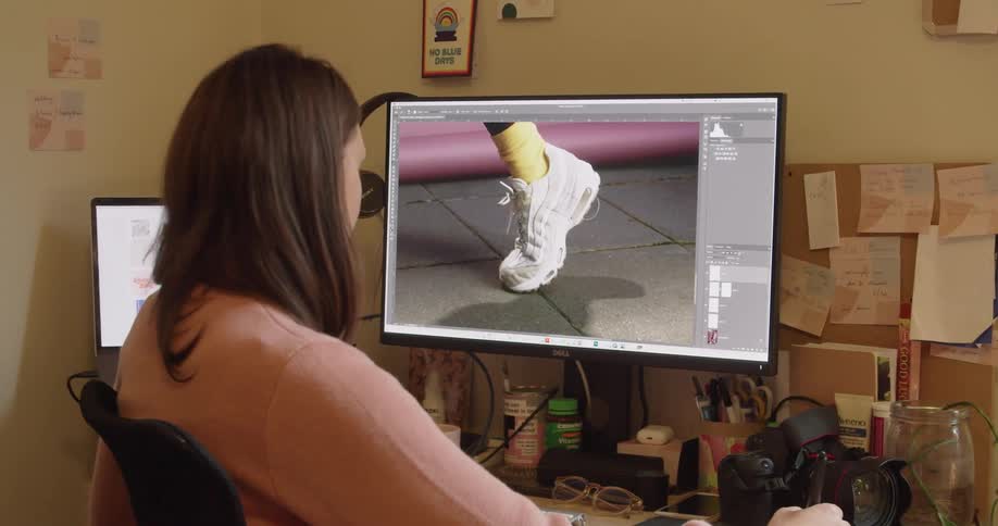 A woman sitting in front of a computer editing a photo