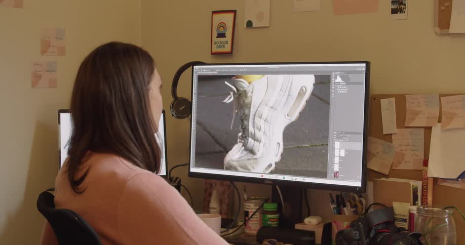 A white woman sits at a desk and works on a computer