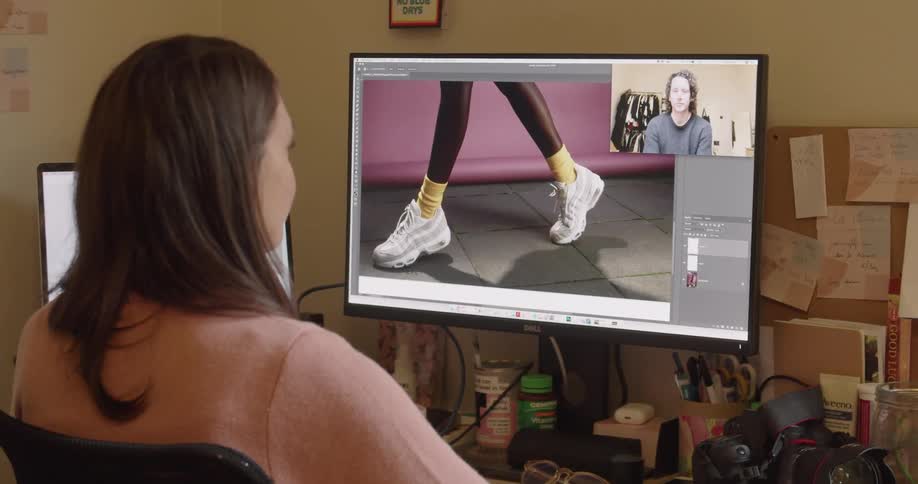 Woman has a video chat with another woman while looking at clothing being modeled on the monitor
