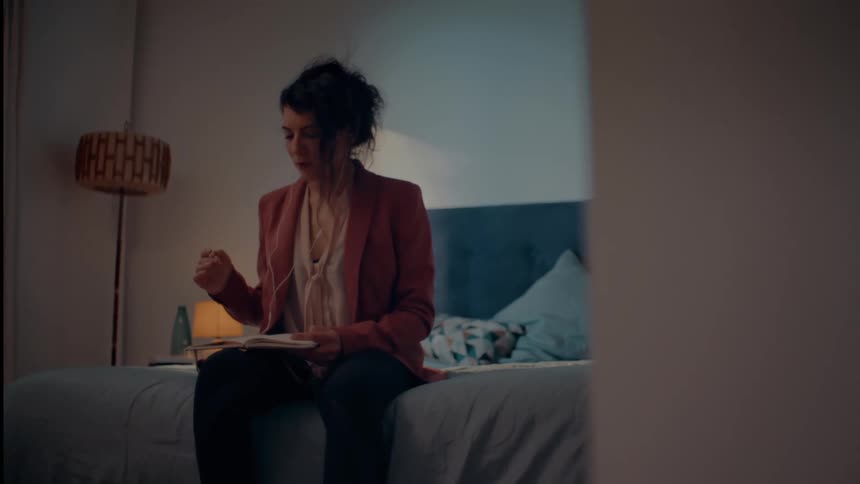 Woman sitting in bed gets inspired while writing in notebook