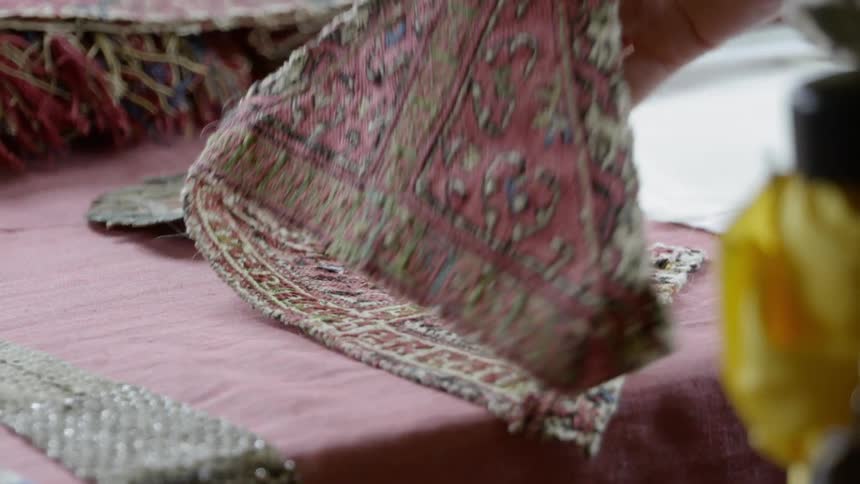 A woman picks up a piece of patterned cloth from a table