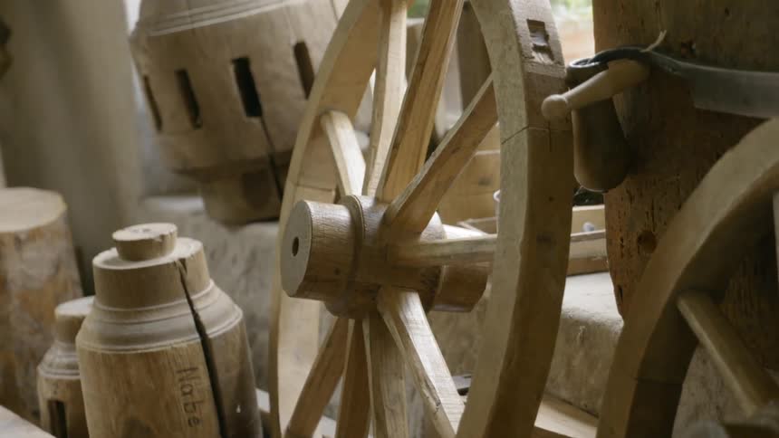 A wooden carriage and other old wooden objects stored in a stone room