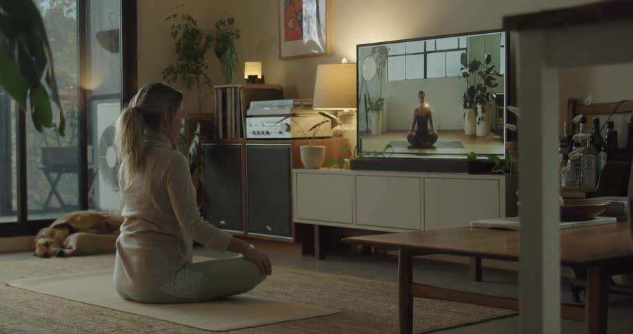 Woman doing yoga workout indoors from video class on tv