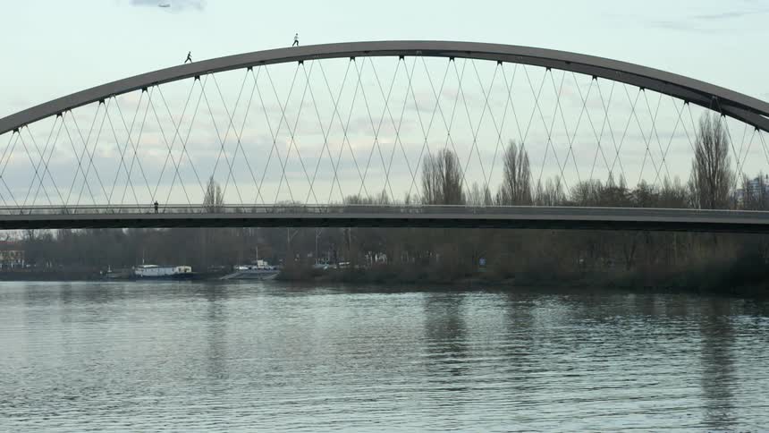 Two people run over the arch of a bridge over the river