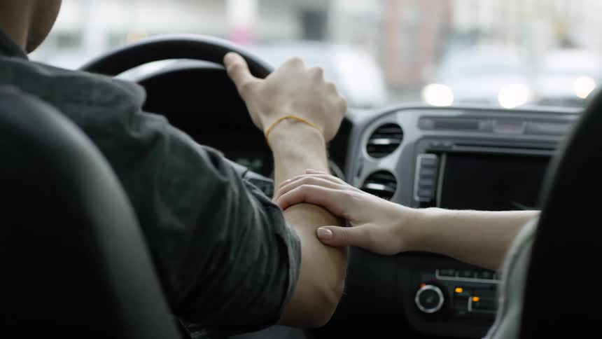 Man drives car while woman rest her hand on his arm