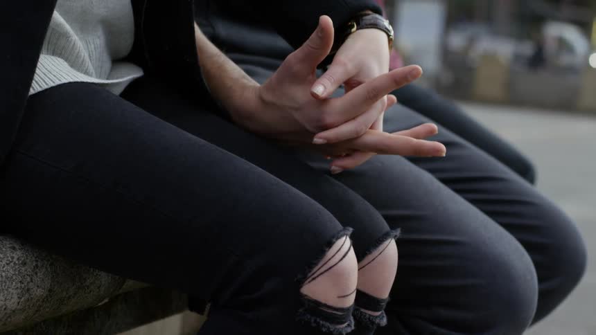 A man and woman sit together and hold hands