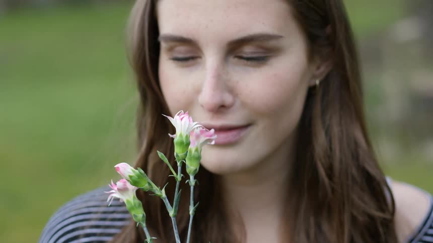 A girl is smelling a flower