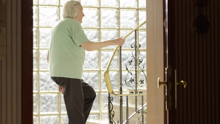An elderly white woman climbs a flight of stairs
