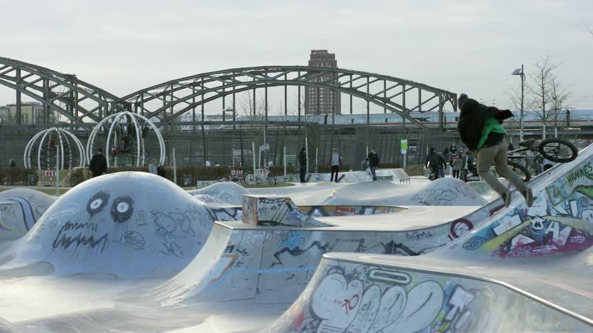 Teenagers skating and biking over jumps at a park