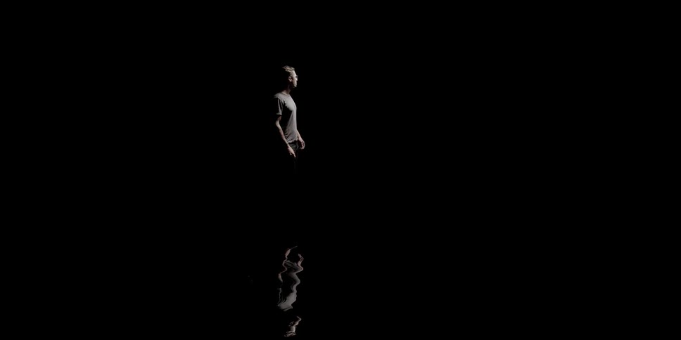 Man stands in the spotlight against the pitch black background