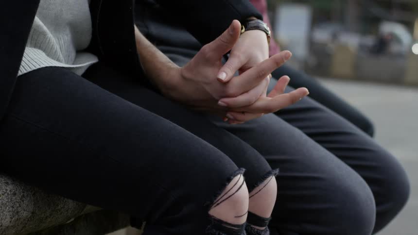 Couple sits downtown near street holding hands