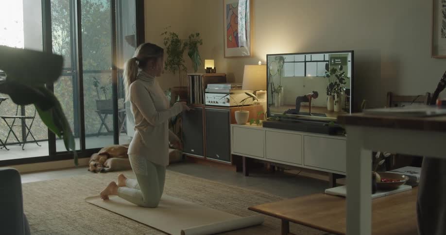 Woman practices yoga viewing yoga instructor on television