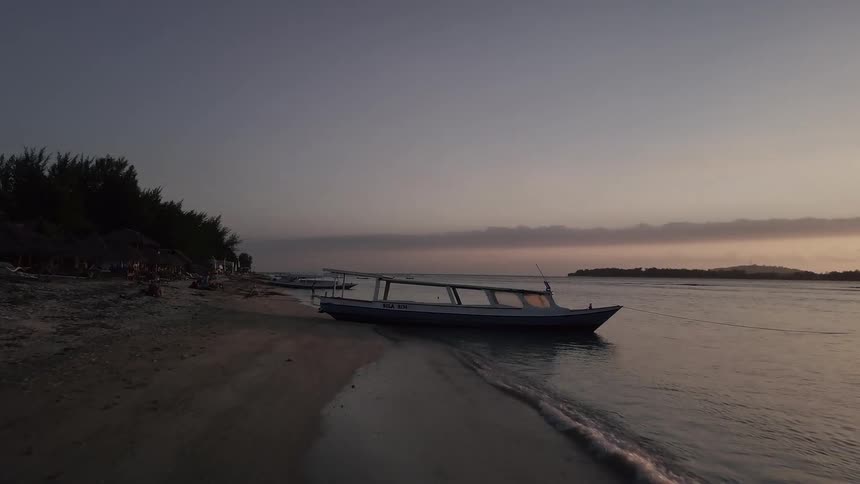 Some people are playing on the beach near a couple of boats