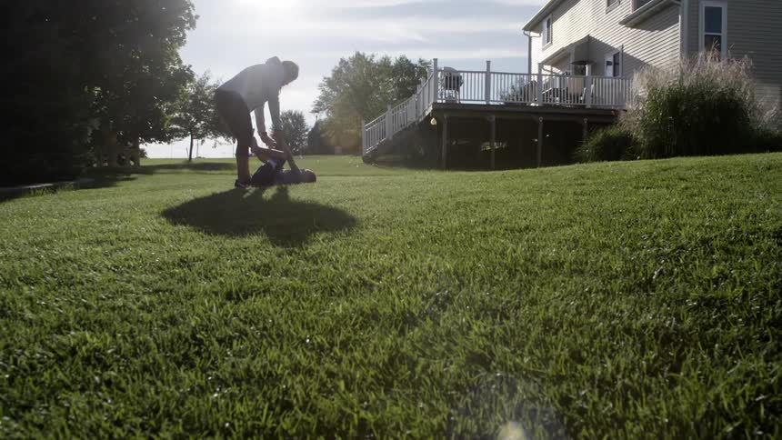 Mom and son play on the green grass in the garden