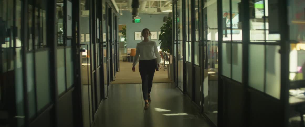 A woman walks down a corridor in an office