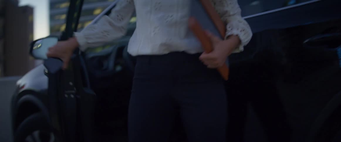 A woman steps out of her car and uses her cell phone as she walks