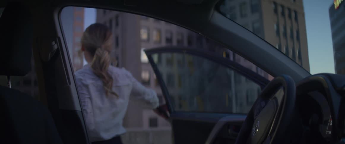 A woman grabs her purse and exits her car