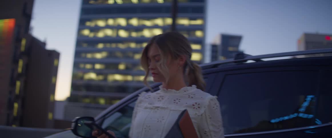 A white woman gets out of a vehicle and walks across a parking garage