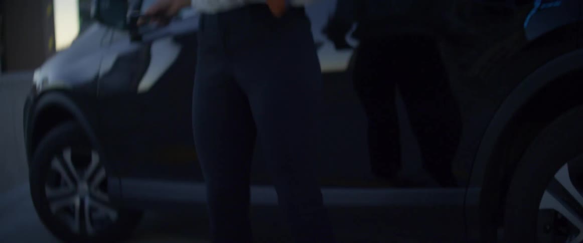 A woman gets out of her car and uses her cell phone as she walks
