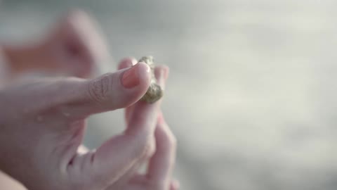 A white woman rolls a small rock around with her fingers