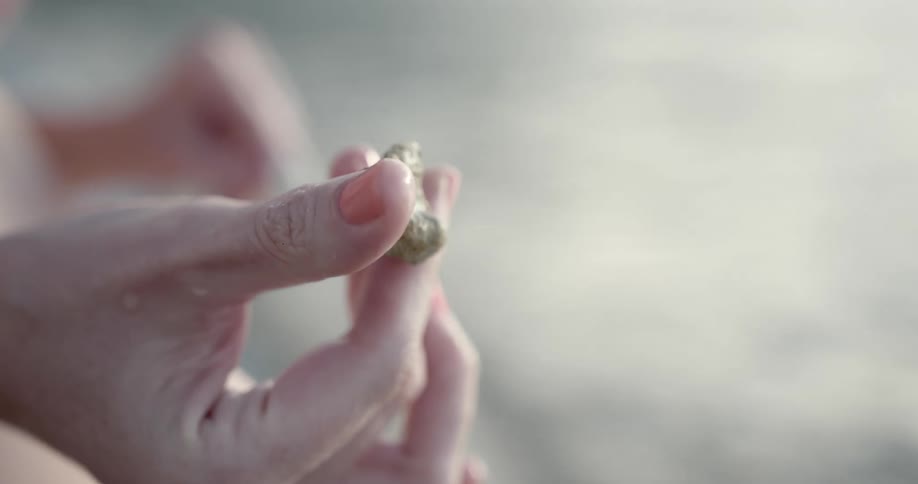 A white woman rolls a small rock around with her fingers
