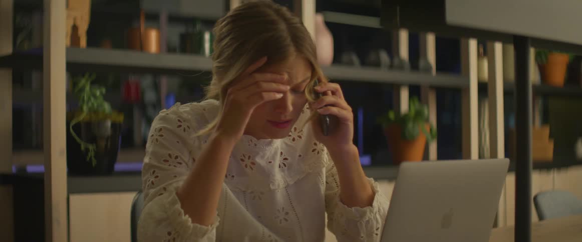 Woman working on laptop in office answer mobile phone and becomes upset