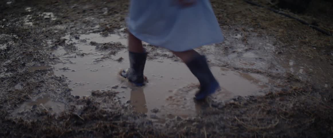 A child is running through the mud in a rural area