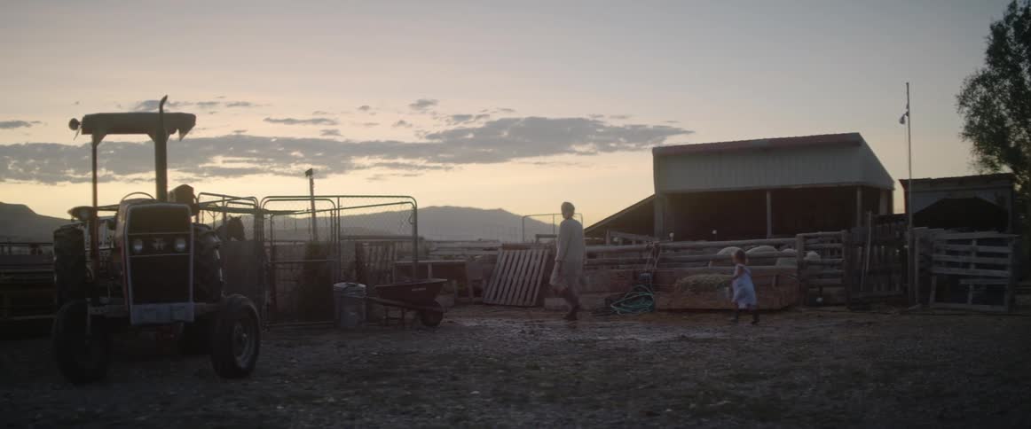 Mother and daughter walk throuhg farm corral at sunset