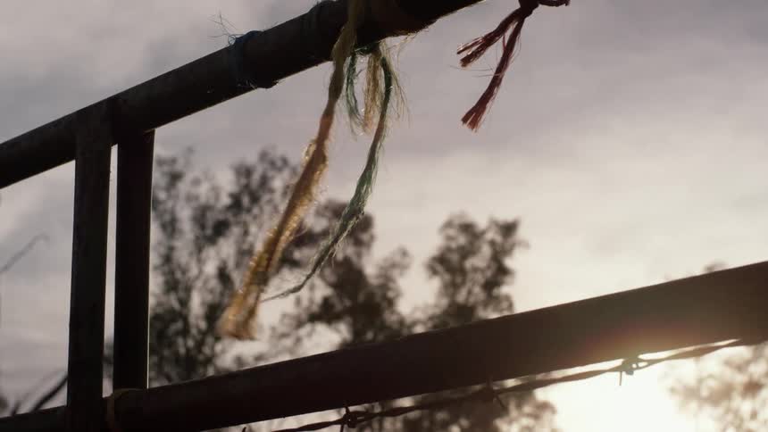 A fence with barbed wire and rope tied on it