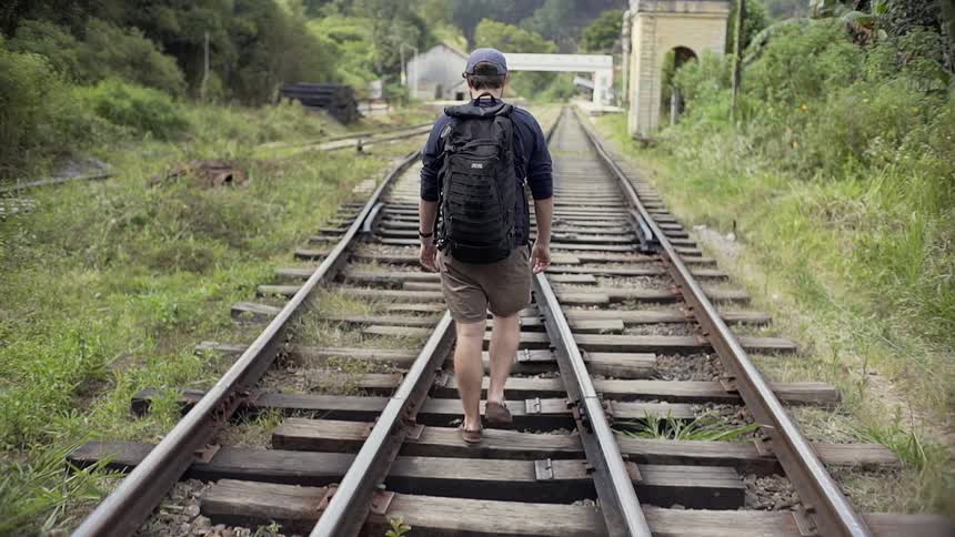 A man hikes on the railroad tracks
