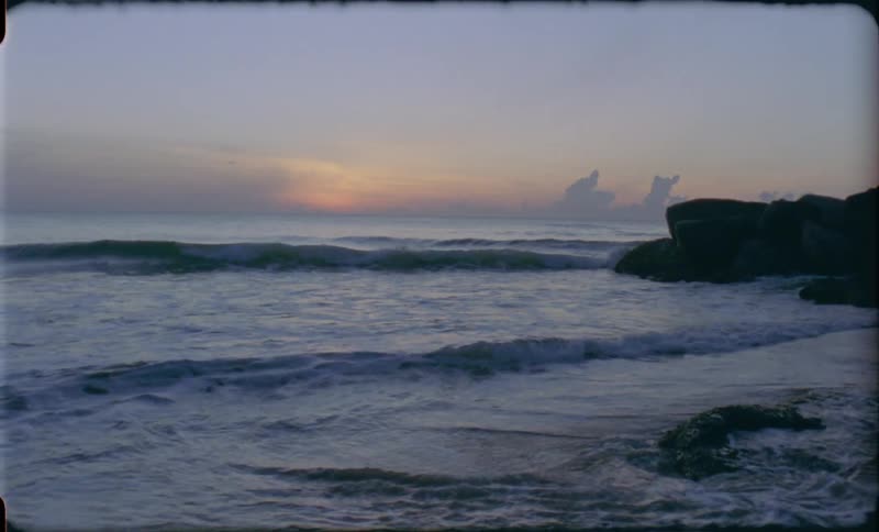 Waves washing up on a beach with the sky in the background