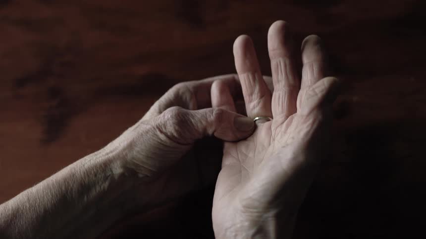 Elderly person plays with wedding ring on finger