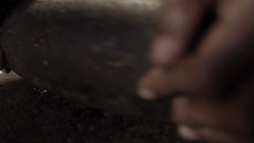 A person is rubbing a stone over grain to grind it