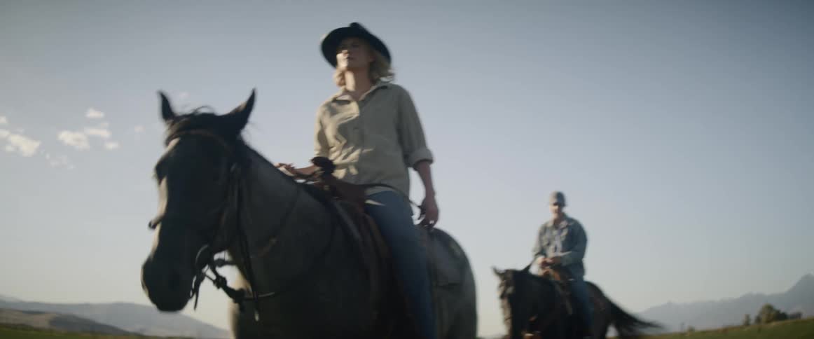 Two people ride a horse on a sunny day