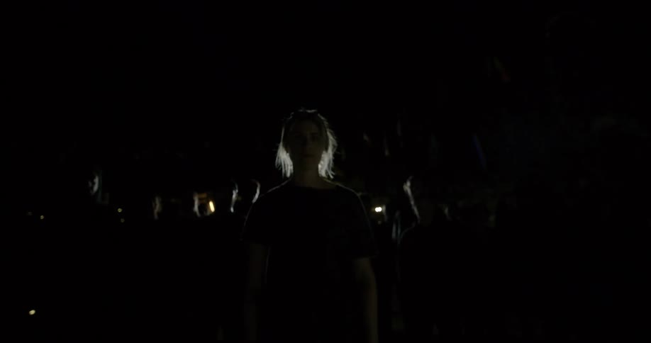 A woman standing with her back towards a crowd of people all facing the camera