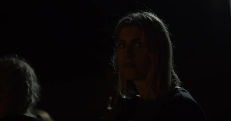 A woman standing with a group turns her head looking anxious