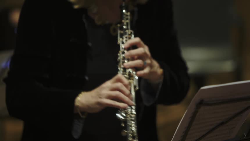 A person is playing a musical instrument in front of sheet music
