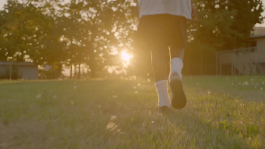 A young boy walks across a lawn towards a house