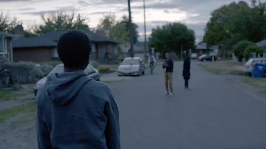 A group of young friends play catch on a suburban street
