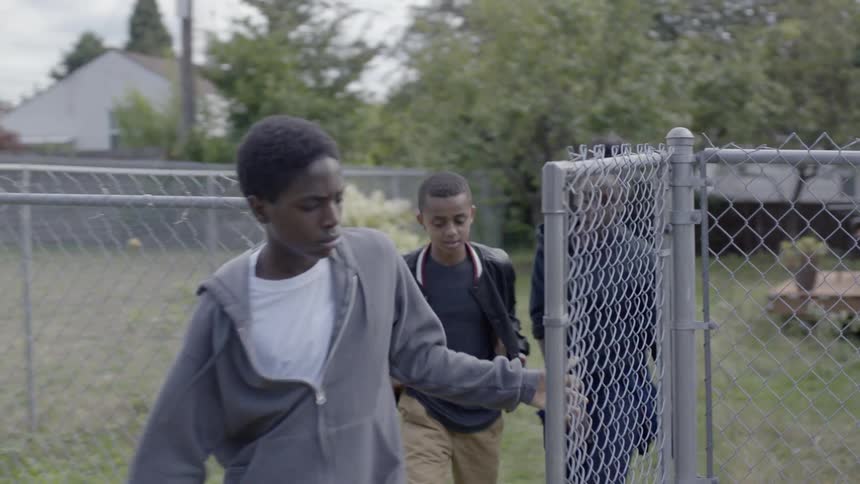 Two boys and a girl walk through a backyard and out the fence