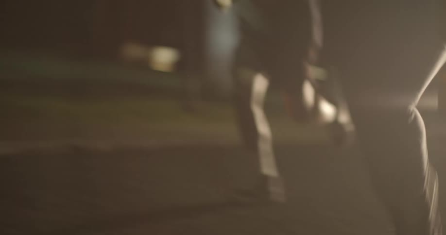 People run on the road in front of a vehicle illuminating the road ahead with headlights
