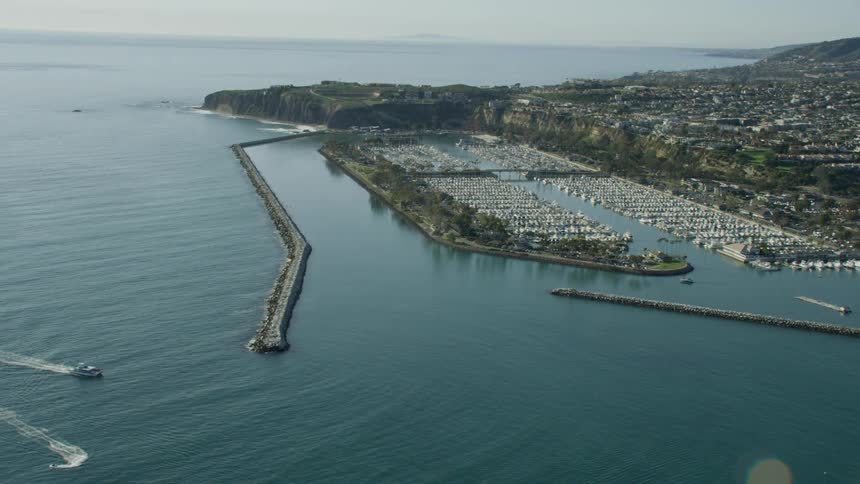Slow motion aerial view of boats transiting near a marina in Southern California