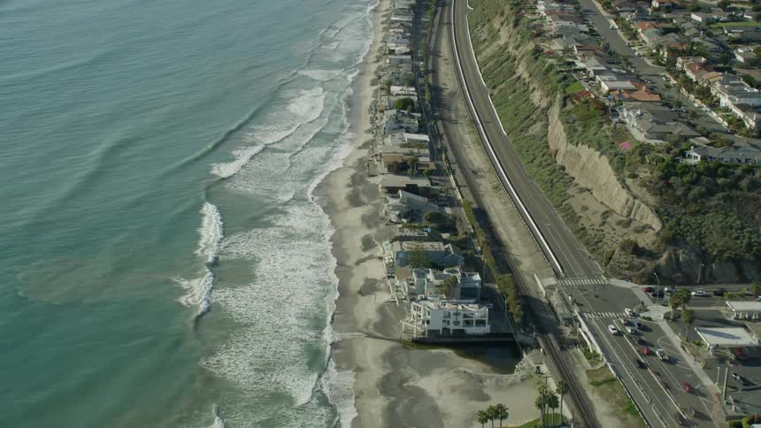 Slow motion aerial view of waves rolling into shore along the PCH