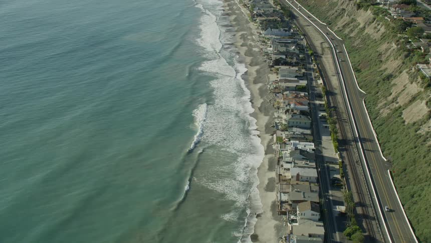 Slow motion aerial footage of beachside homes along the Pacific Coast Highway