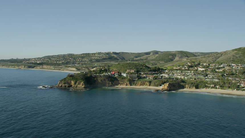 Slow motion aerial view of a helicopter flying near a coastline with tall ocean cliffs